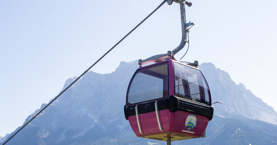 A pink gondola, the Zugspitze in the background | © Tiroler Zugspitz Arena/ Giovanni Frey