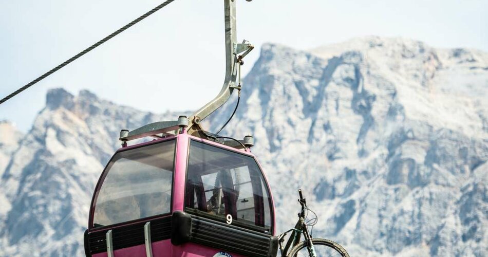 A pink gondola with a bike, with the Zugspitze in the background | © Tiroler Zugspitz Arena/Nikola Radovic