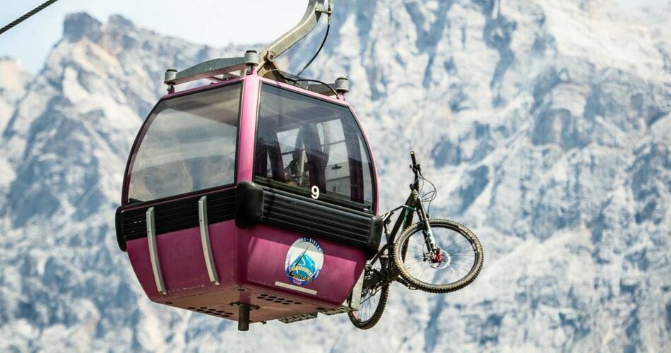 A pink gondola with a bike, with the Zugspitze in the background | © Tiroler Zugspitz Arena/Nikola Radovic