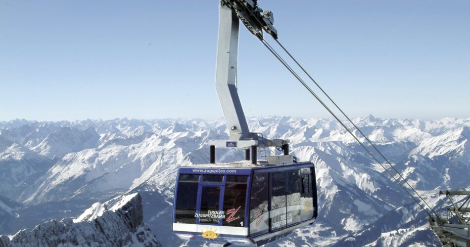 A large gondola lift going to the top of the snowy Zugspitze.