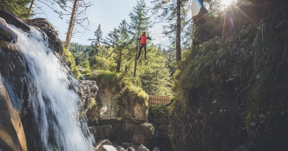 Climber walking on a wire rope, on the left the Häselgehr waterfall. | © Tiroler Zugspitz Arena/C. Jorda