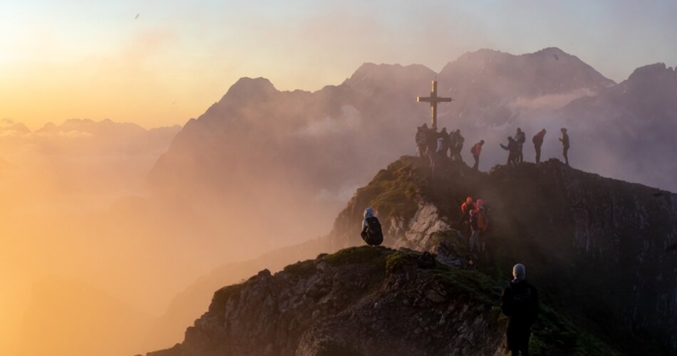 Gipfelkreuz auf felsigem Gipfel im Sonnenaufgang.  | © AnneKaiser