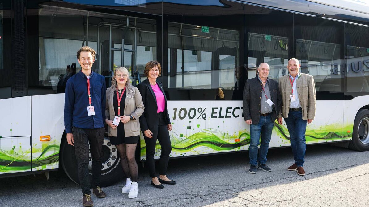 Die Geschäftsführerin der Tiroler Zugspitz Arena steht mit weiteren Teilnehmern des AlpenKlimaGipfels vor einem E-Bus | © Franz Oss