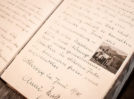 Ein altes Buch mit alter Schrift und einem Schwarz-Weiß-Bild von Kindern | © Tiroler Zugspitz Arena/Bianca McCarty