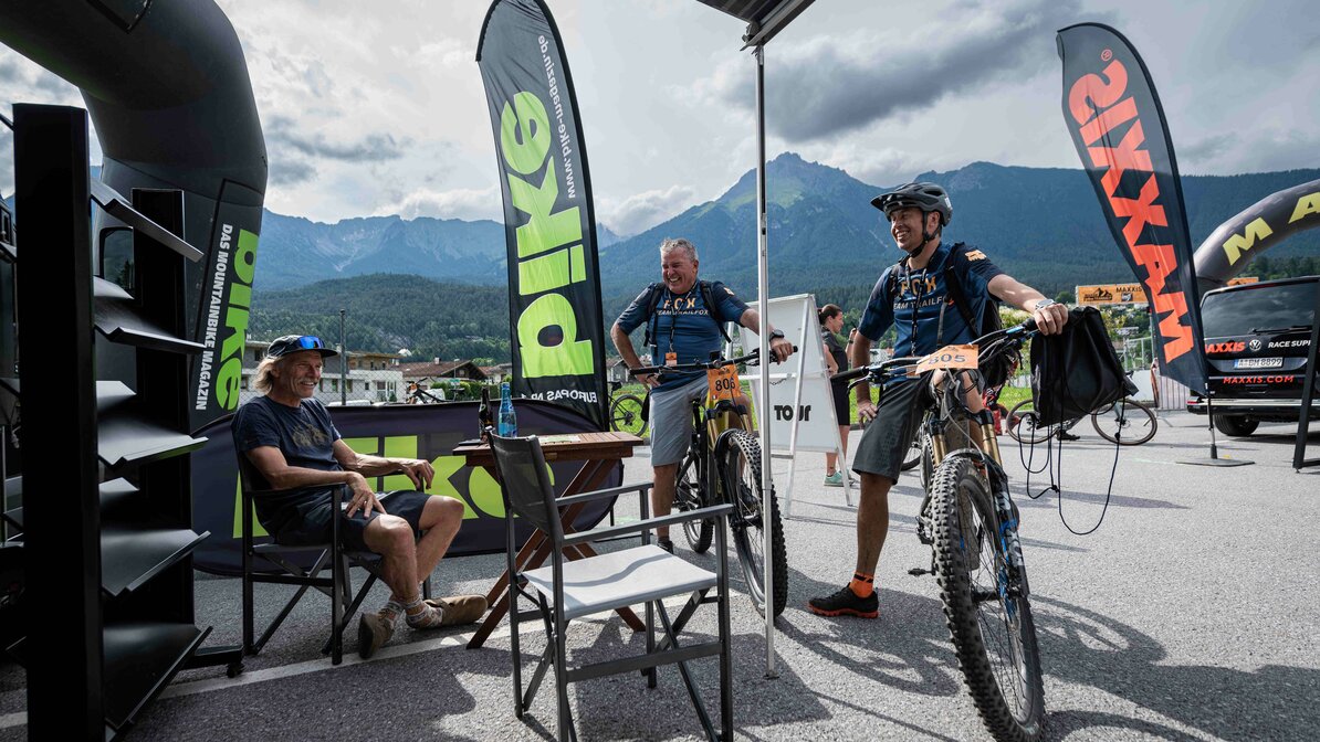 Two mountain bikers talk to a man at an exhibition stand | © Igor Schifris