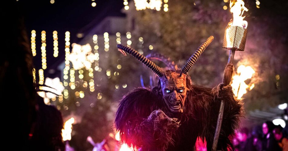 A person with a typical tyrolean Krampus costume and mask, carrying a torch | © Tiroler Zugspitz Arena/Moos Tuifl Ehrwald