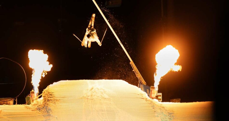 Ein Profi-Skifahrer springt über eine Schanze, daneben Feuer-Show | © Tiroler Zugspitz Arena