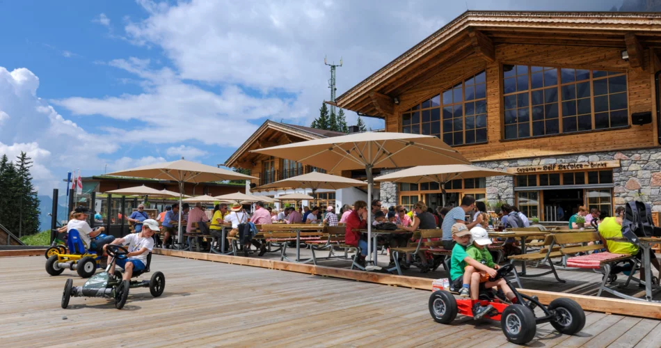 Terrasse auf welcher Kinder mit Tretautos fahren, im Hintergrund eine Hütte | © Tiroler Zugspitzbahn