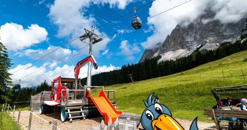 Spielplatz in Form eines Pistenbullys , im Hintergrund eine Bergbahn und Bergpanorama | © Tiroler Zugspitzbahn