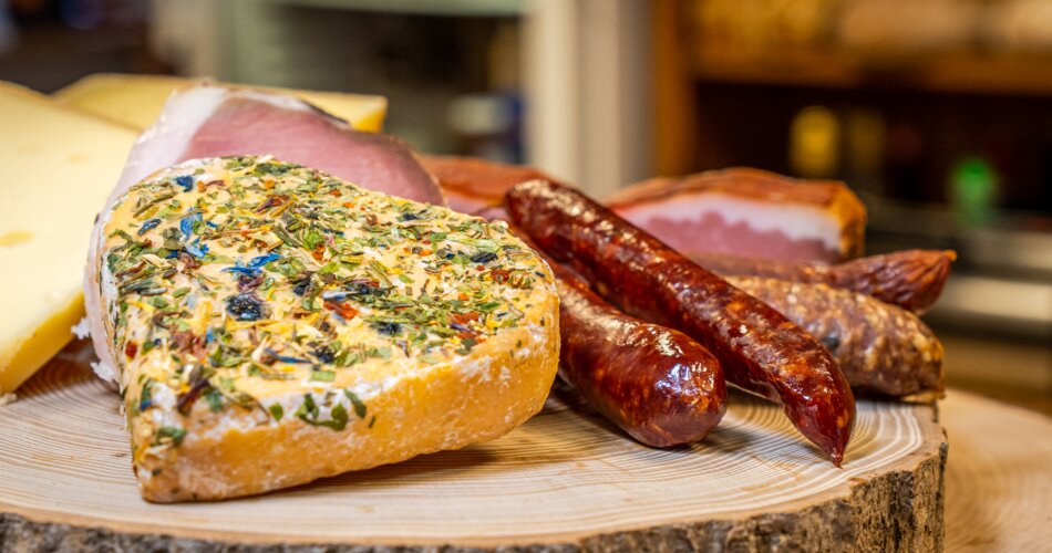 Eine typische Tiroler Brotzeitplatte mit Speck, Käse und Kaminwurzen