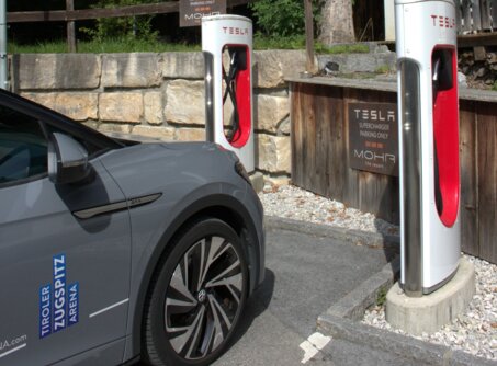 A gray car parked next to two white Tesla e-charging stations | © TZA