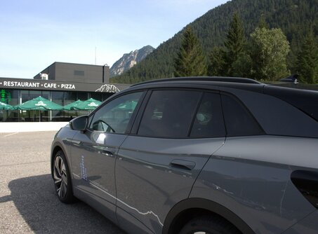 Opposite a gray car you can see a rest stop. There you can read Restaurant, Cafe, Pizza on a black background. | © TZA