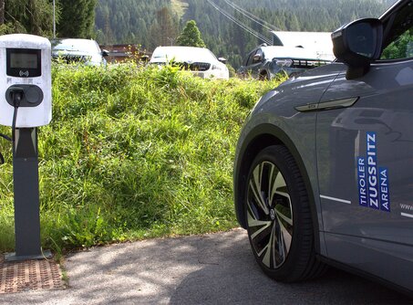 A gray car, next to it a white e-charging station | © TZA
