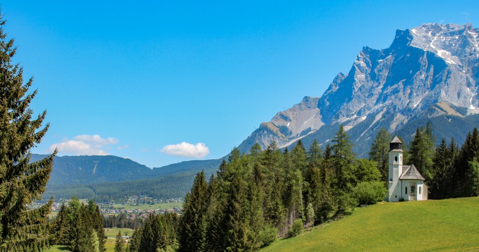 A church, blooming meadows, and the Zugspitze | © Tiroler Zugspitz Arena