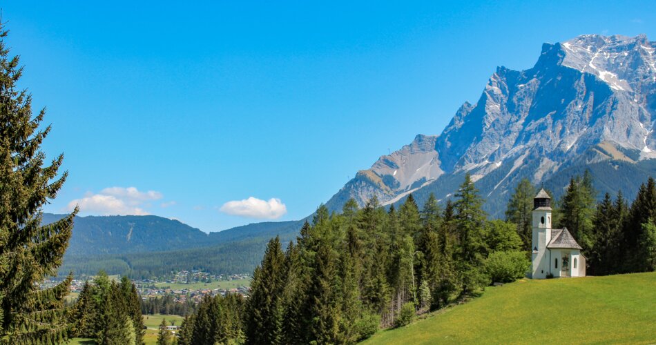 Kirche, blühende Wiesen und die Zugspitze