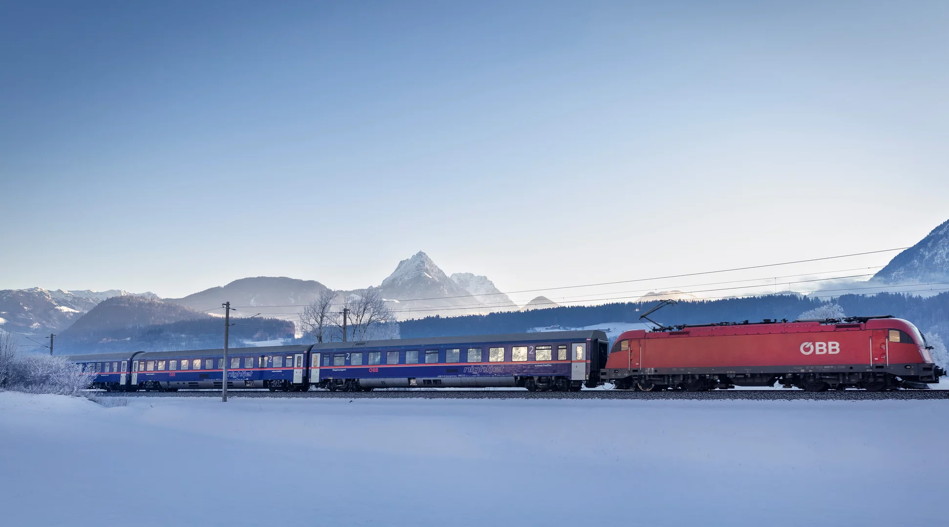 Nightjet | © Harald Eisenberger The ÖBB Nightjet travels through a snowy winter landscape, with a wintry mountain panorama in the background | © Harald Eisenberger