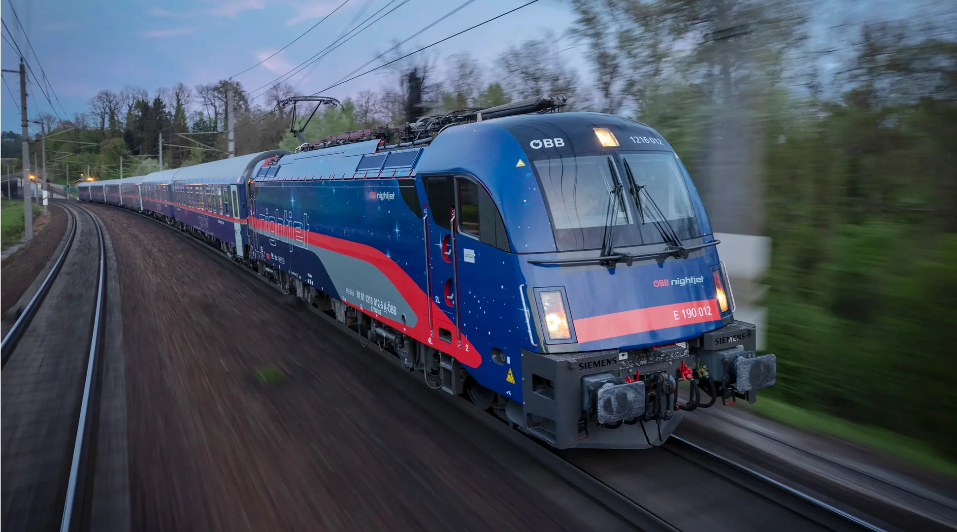 Nightjet | © Harald Eisenberger A blue and red ÖBB Nightjet train travels through a rural landscape | © Harald Eisenberger