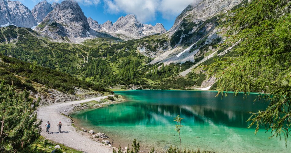 Two mountain bikers on a path next to the turquoise Seebensee, surrounded by an impressive mountain panorama | © Tiroler Zugspitz Arena