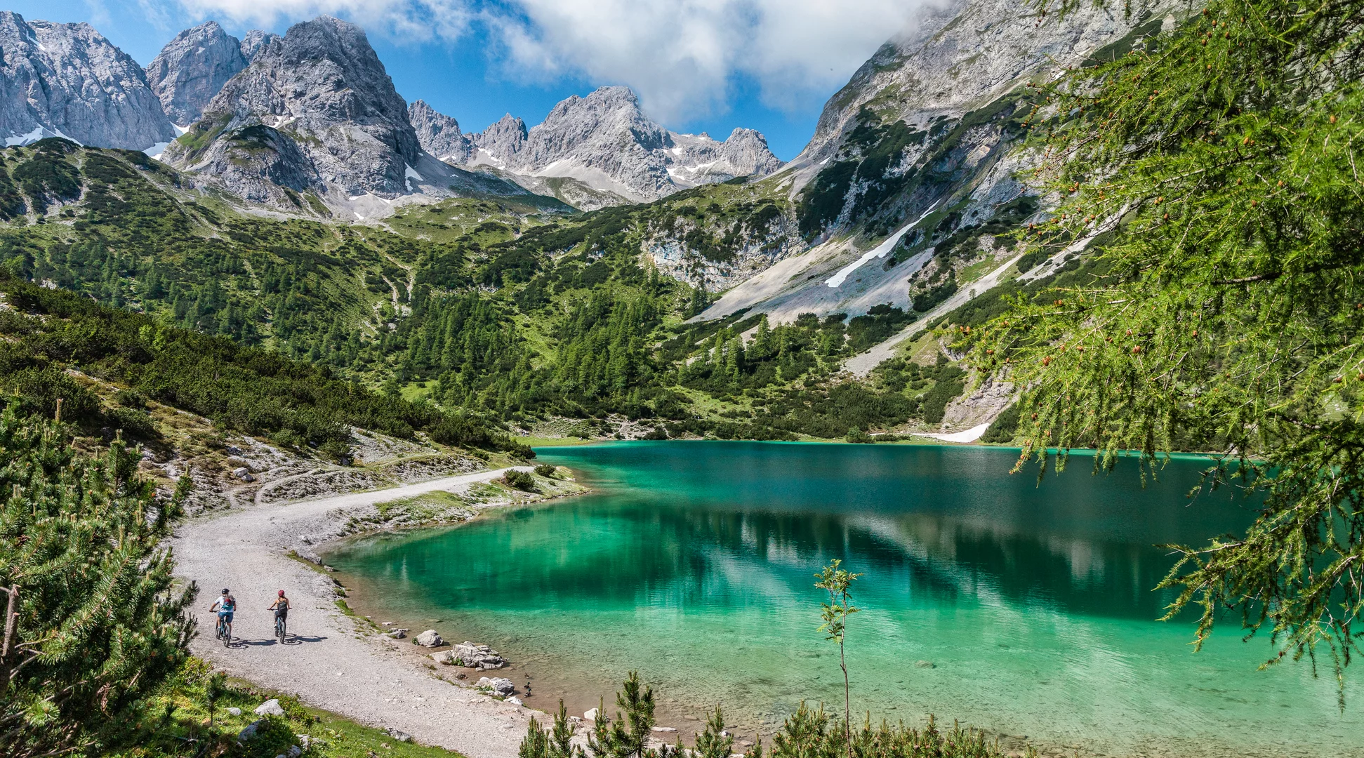 Mountainbiking at the lake Seebensee | © Tiroler Zugspitz Arena Two mountain bikers on a path next to the turquoise Seebensee, surrounded by an impressive mountain panorama | © Tiroler Zugspitz Arena