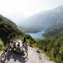 Bikers stand at a viewpoint overlooking Lake Blindsee | © KLEMENS KOENIG