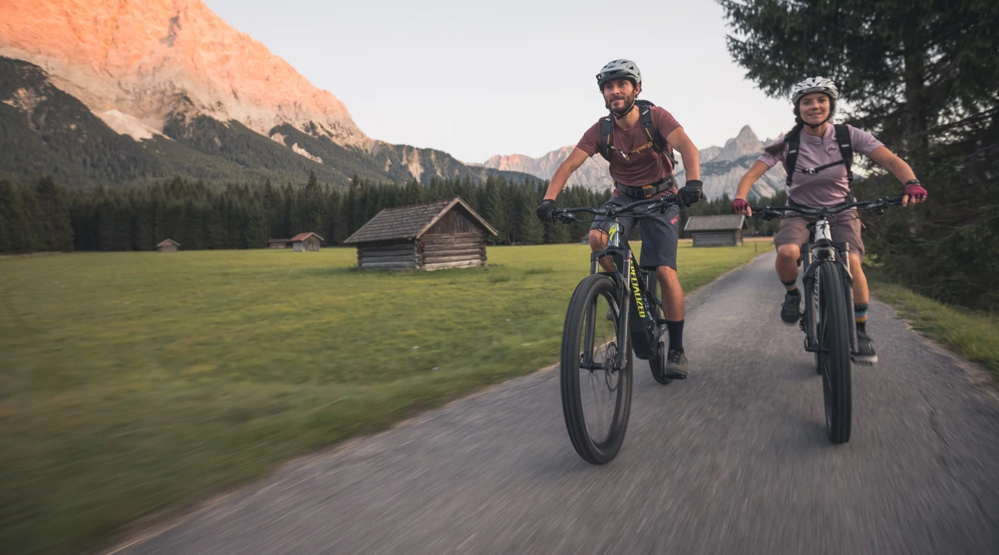 Biking | © Tiroler Zugspitz Arena/C. Jorda Two cyclists on a path, behind them a mountain illuminated by the evening sun | © Tiroler Zugspitz Arena/C. Jorda