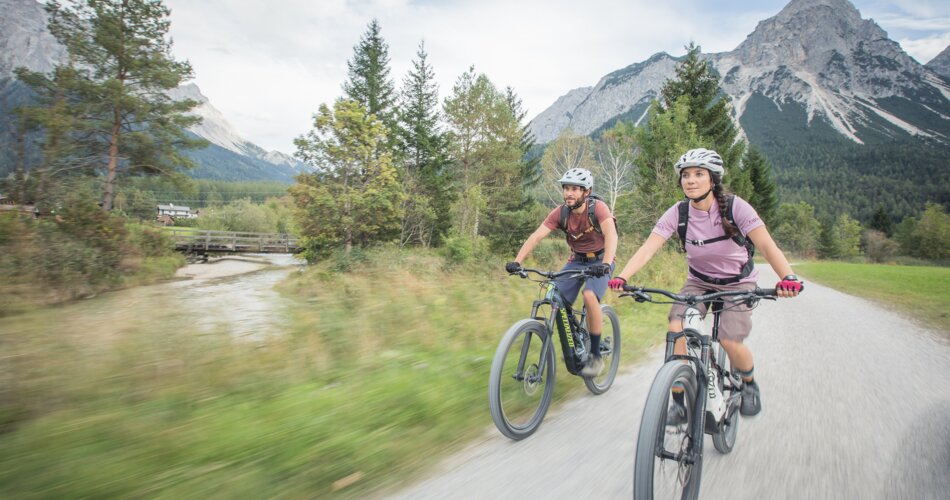 A couple biking in the valley along the river | © Tiroler Zugspitz Arena/ C.Jorda