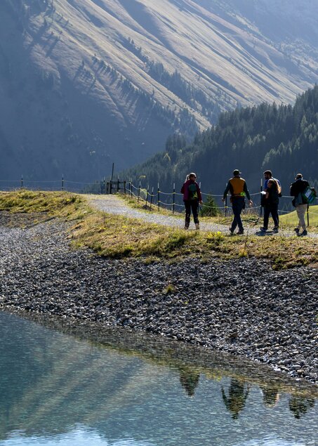 Eine Gruppe wandert am Ufer eines kleinen Sees