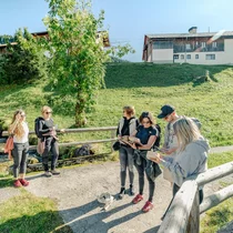 Eine Gruppe steht auf einer Brücke, welche über einen kleinen Bach führt. Sie sind dabei gemeinsam ein Rätsel zu lösen. | © Tiroler Zugspitz Arena/Schennach Valentin