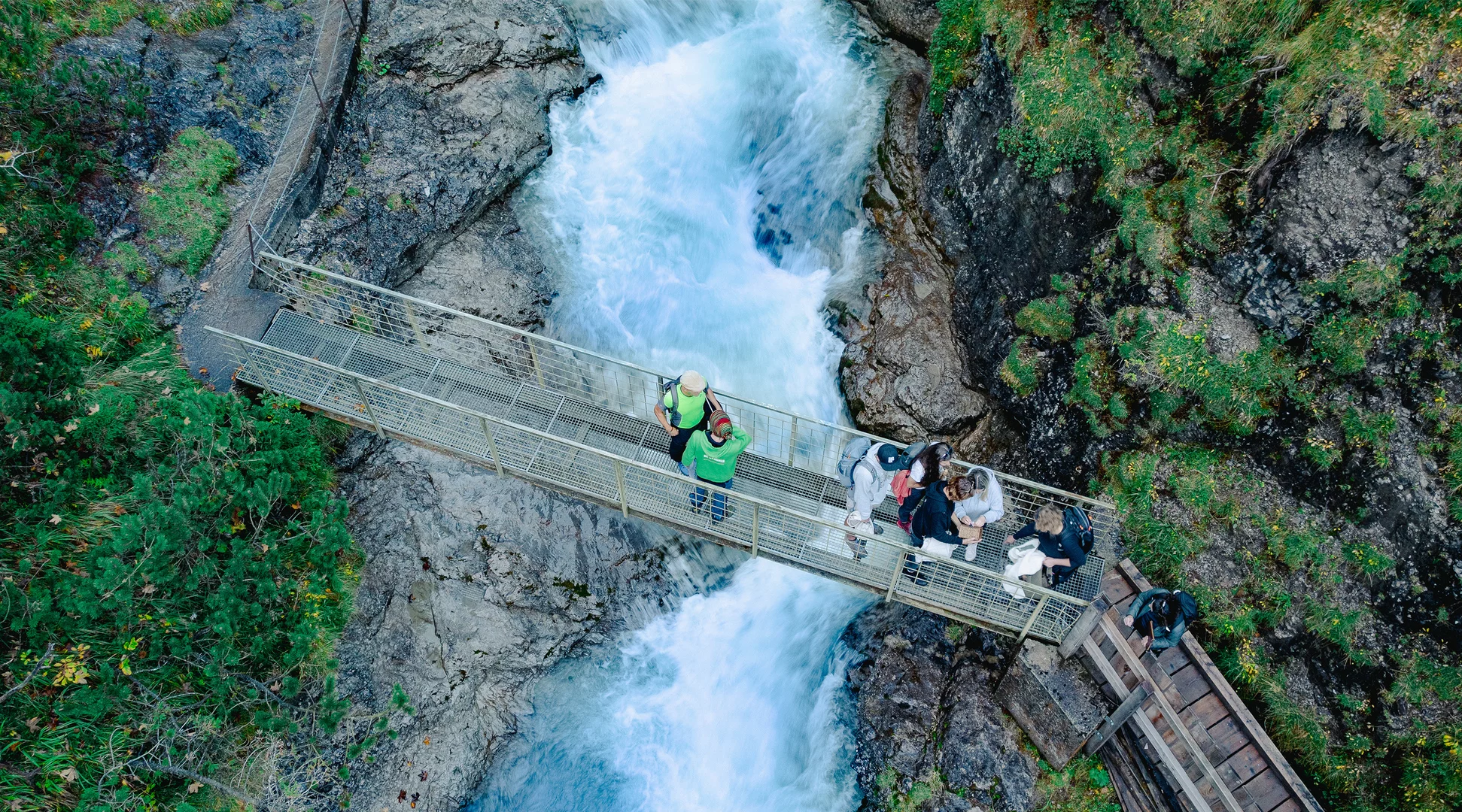 Escape trail the secret of the high alpine spirit | © Tiroler Zugspitz Arena/Schennach Valentin Several hikers on a bridge over a beautiful blue mountain stream | © Tiroler Zugspitz Arena/Schennach Valentin