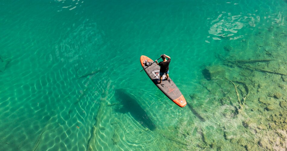 Ein Stand-Up-Paddler auf dem Heiterwanger See mit seinem türkises Wasser | © Tiroler Zugspitz Arena/ Sam Oetiker