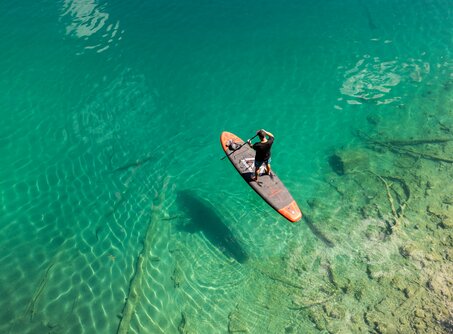 Ein Stand-Up-Paddler auf dem Heiterwanger See mit seinem türkises Wasser | © Tiroler Zugspitz Arena/ Sam Oetiker