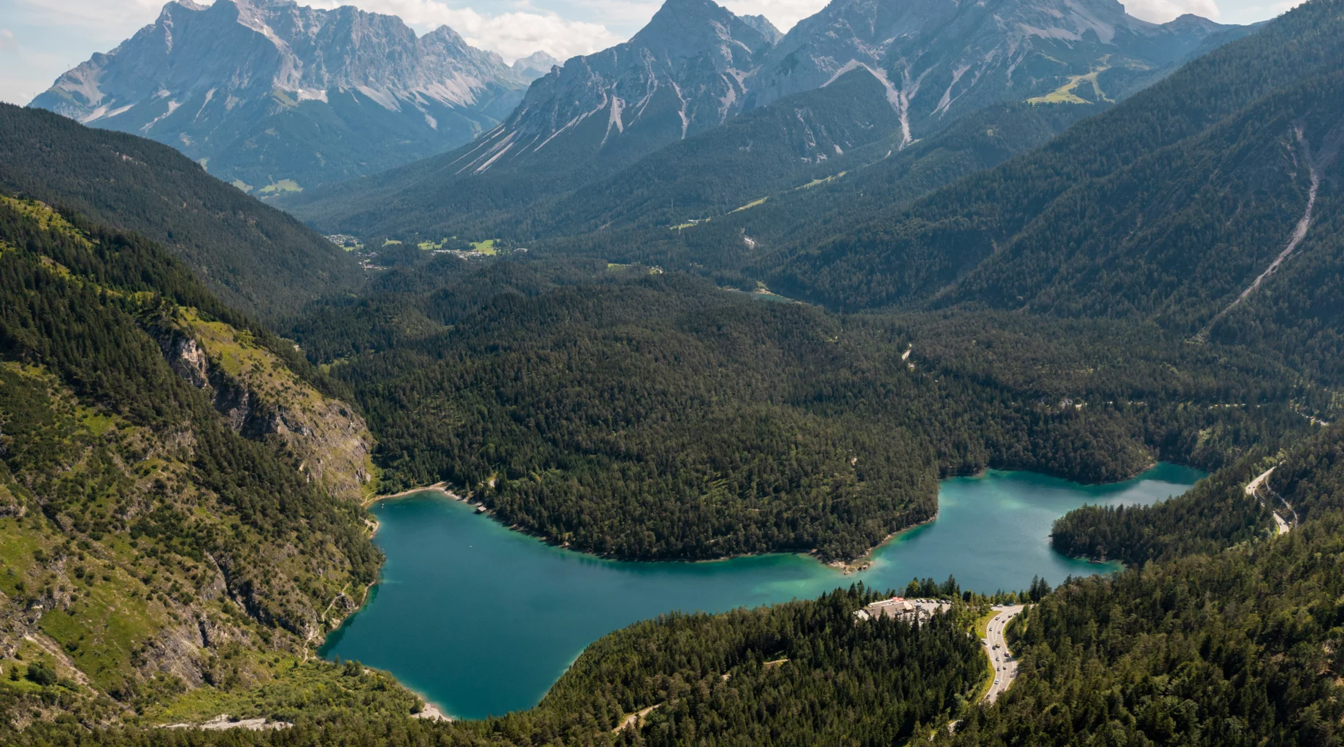 Lake Blindsee - Tiroler Zugspitz Arena | © Tiroler Zugspitz Arena/Sam Oetiker A drone shot of a turquoise-colored mountain lake in front of an imposing mountain backdrop | © Tiroler Zugspitz Arena/Sam Oetiker