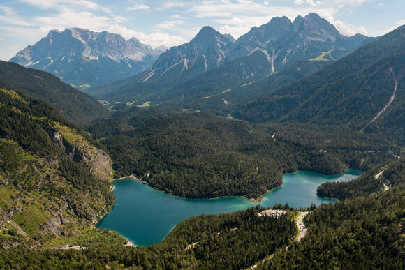 A drone shot of a turquoise-colored mountain lake in front of an imposing mountain backdrop | © Tiroler Zugspitz Arena/Sam Oetiker