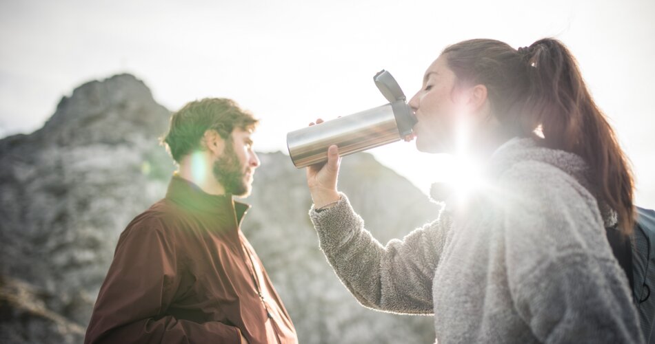 Two hikers, a man and a woman, the woman is having a drink. A rocky peak in the background | © Tiroler Zugspitz Arena/C. Jorda