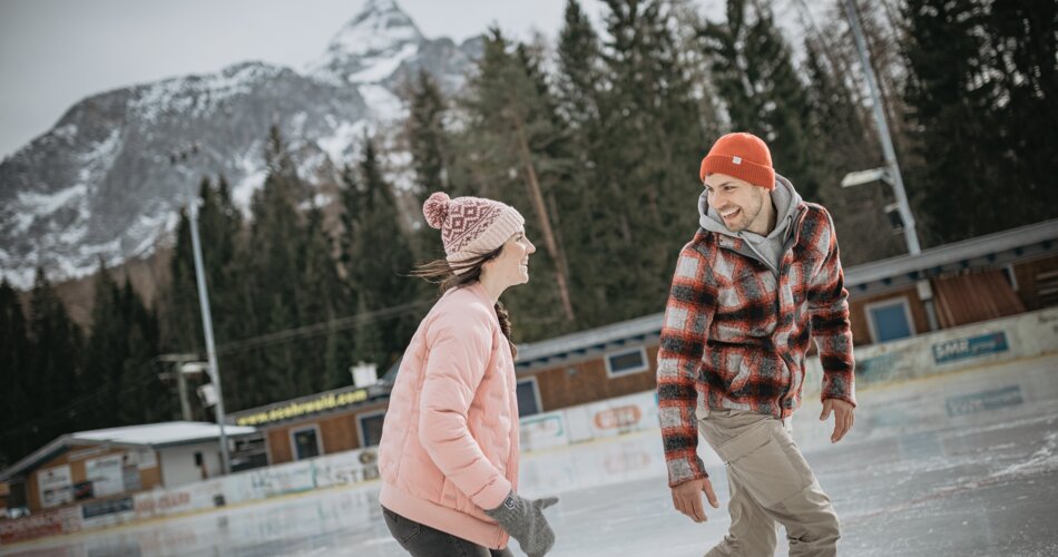 Eine Frau in rosa Jacke, mit rosa Mütze und ein Mann in karierter Jacke, mit oranger Mütze beim Eislaufen. | © (c)ZABT_C. Jorda (40)