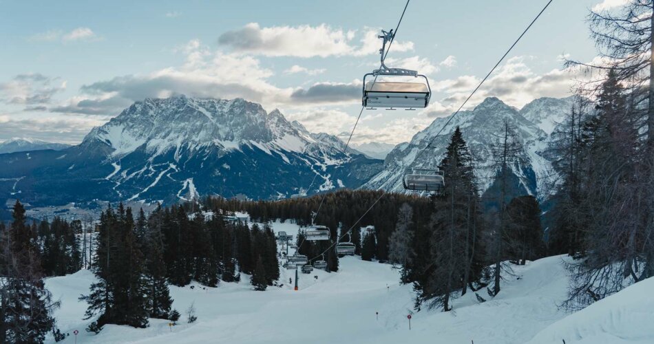 Ein Sessellift über einer frisch präparierten Piste, im Hintergrund Bergpanorama mit der Zugspitze | © Tiroler Zugspitz Arena/Sam Oetiker