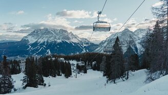 Ein Sessellift über einer frisch präparierten Piste, im Hintergrund Bergpanorama mit der Zugspitze | © Tiroler Zugspitz Arena/Sam Oetiker