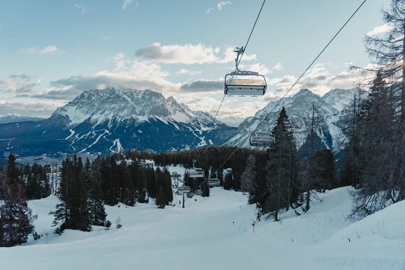 A chairlift above a freshly groomed piste, with the Zugspitze in the background | © Tiroler Zugspitz Arena/Sam Oetiker
