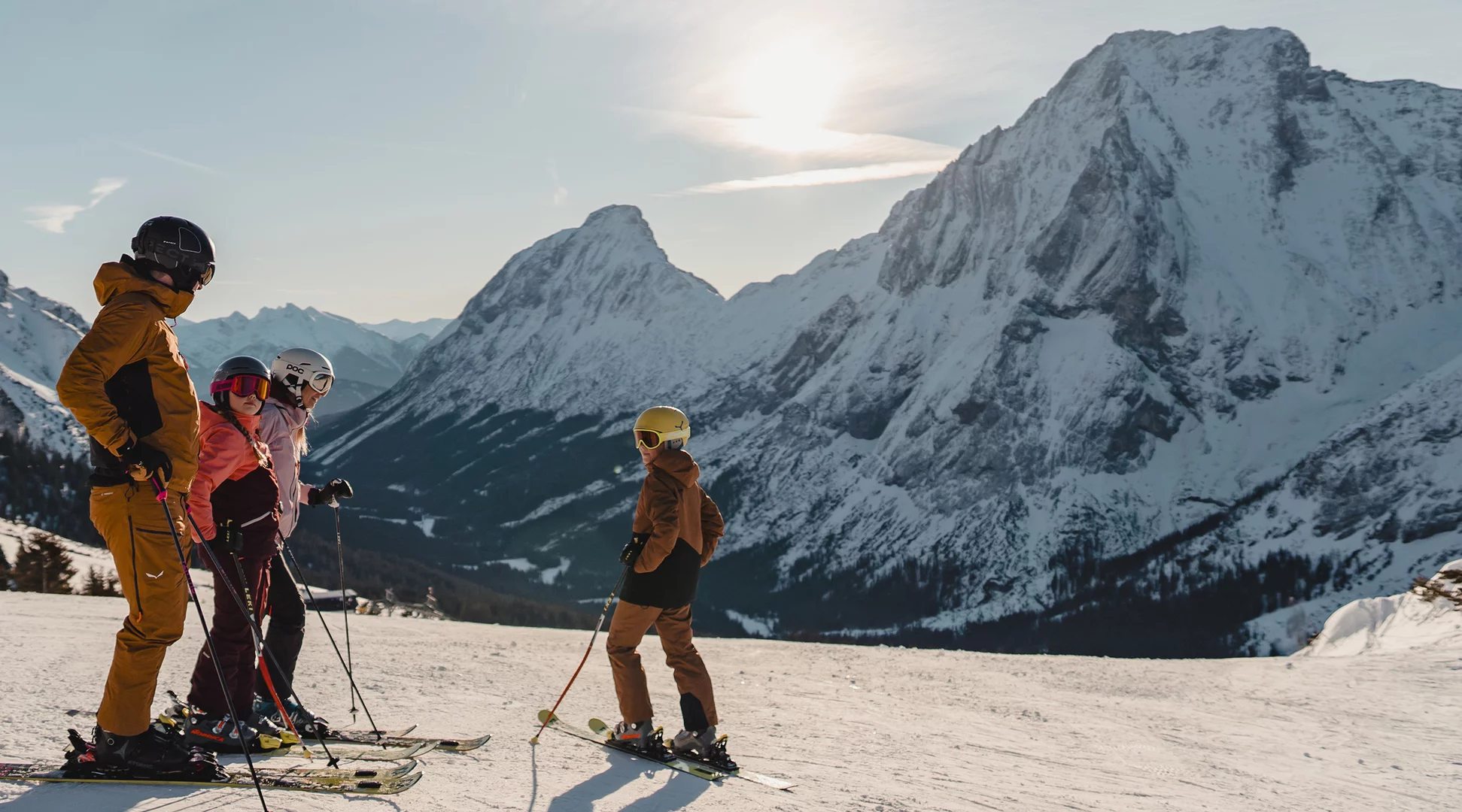 Skifahren Ehrwalder Almbahn | © Tiroler Zugspitz Arena/Sam Oetiker Eine Familie beim Skifahren, sie stehen auf einer breiten, frisch präparierten Piste, im Hintergrund ein hoher Berg | © Tiroler Zugspitz Arena/Sam Oetiker