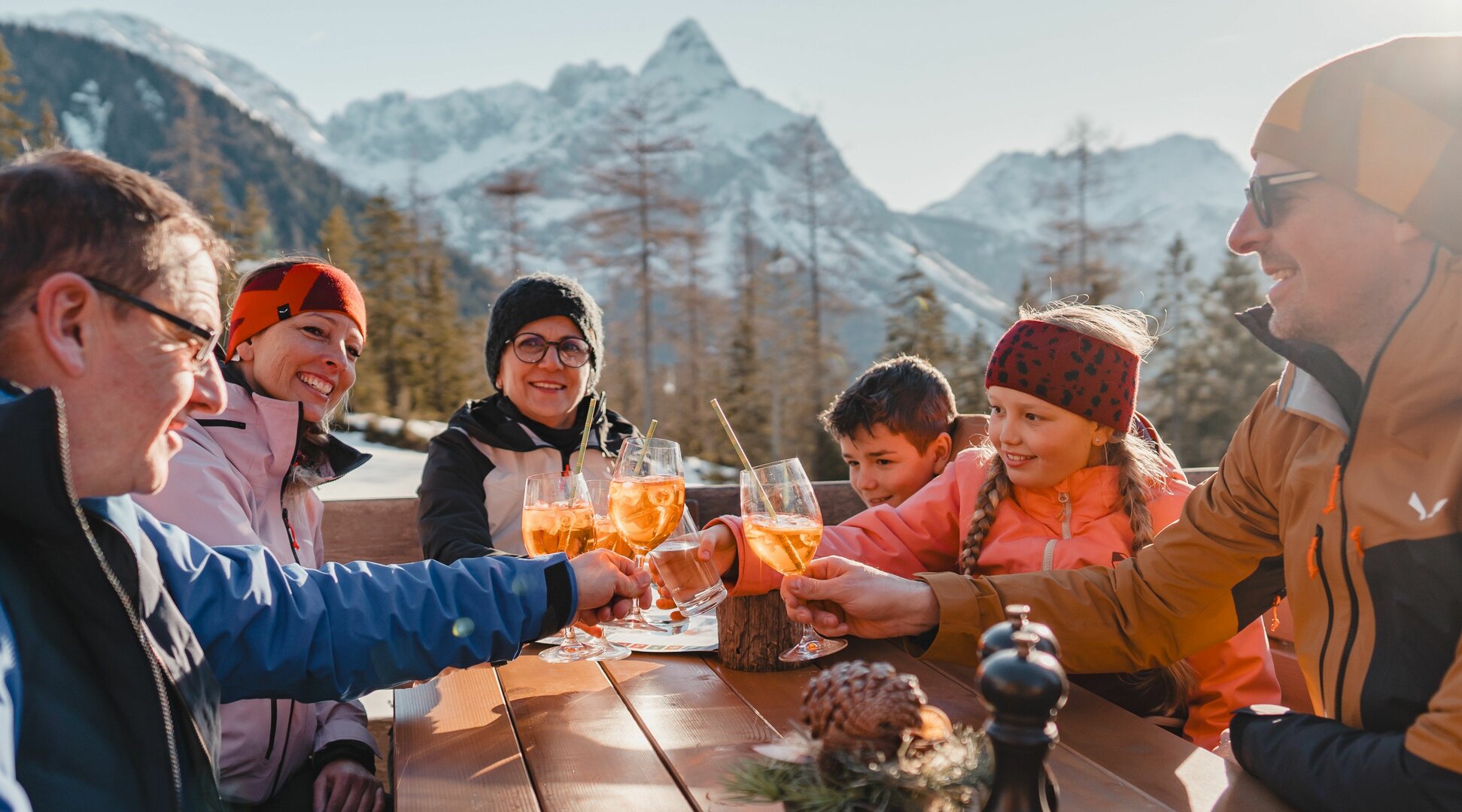 A family sits in the sun and clinks glasses. | © Tiroler Zugspitz Arena/Sam Oetiker