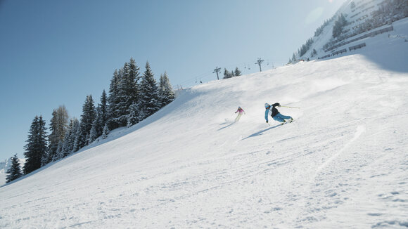 Ein Skifahrerpaar fährt einen Hang in Berwang hinunter.