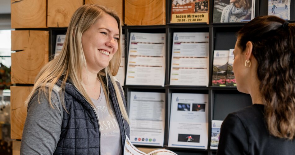 Portrait of a TZA employee in the information office. In the background a beautiful wooden shelf with brochures.