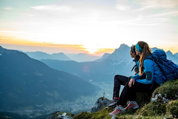 Zwei Wanderinnen genießen zur golden hour die Aussicht in der Tiroler Zugspitz Arena. | © AnneKaiserPhotography