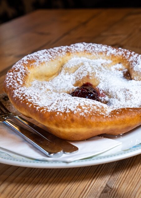 Eine Tiroler Spezialität, in Fett ausgebackener Teigfladen, traditionell mit Puderzucker und Preiselbeeren oder mit Sauerkraut. 